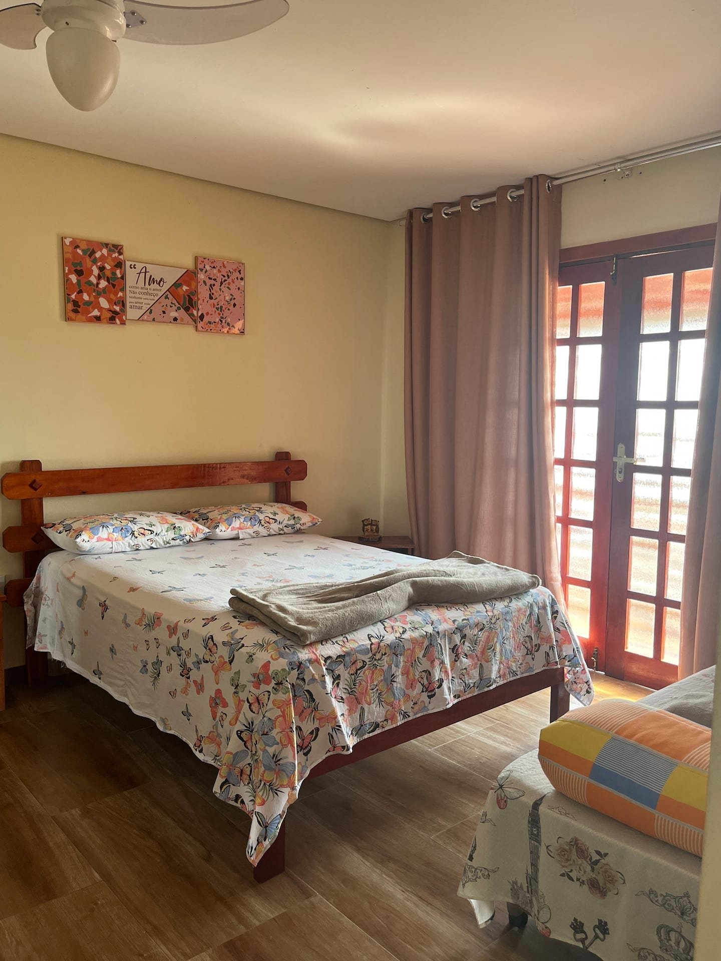 Quarto da casa grande com cama de casal e porta para a varanda.