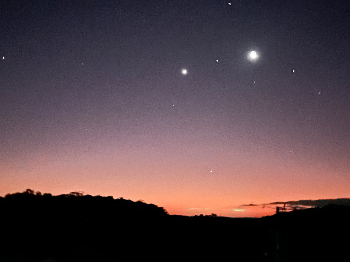 Céu do entardecer sobre a silhueta de morros, fotografado na galeria pública da Casa Borboleta azul.