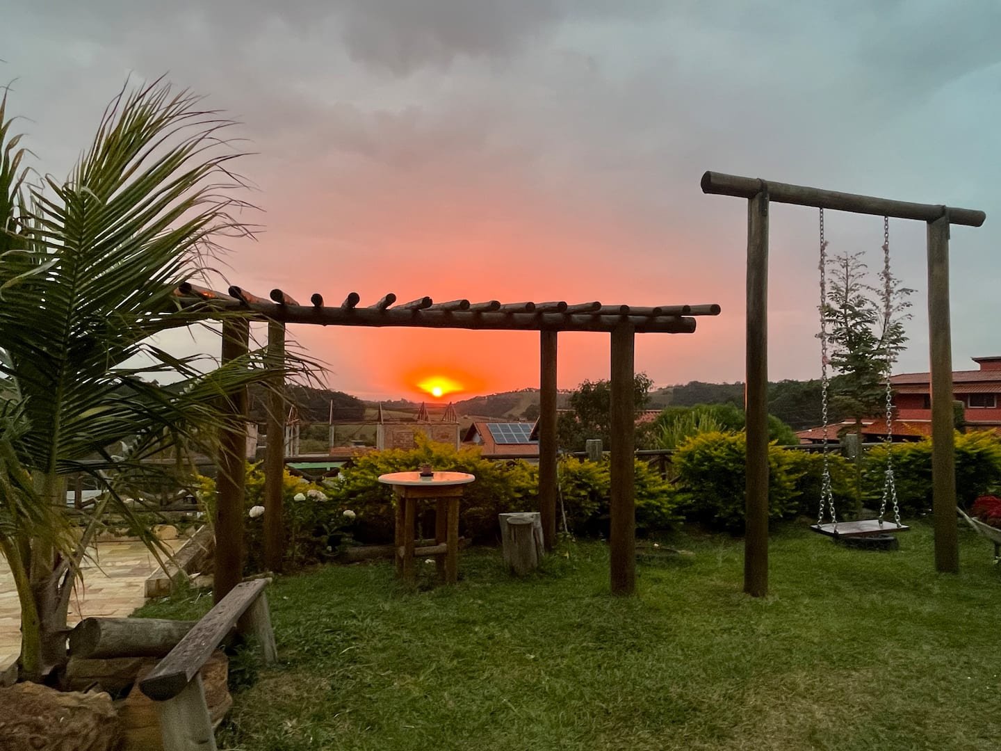 Jardim com balanço, bancos e pergolado ao pôr do sol, publicado na galeria da casa.